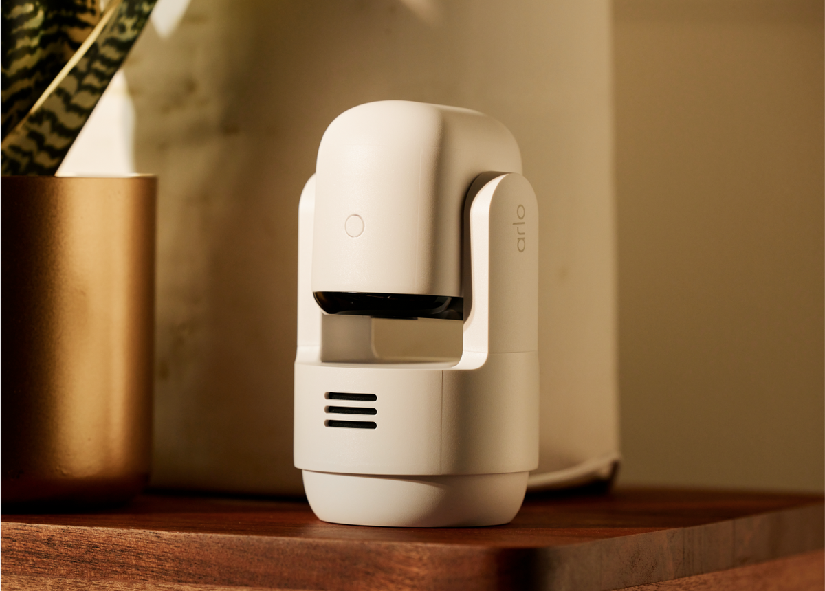 Arlo Essential Pan Tilt Indoor camera on top of a wooden tablet