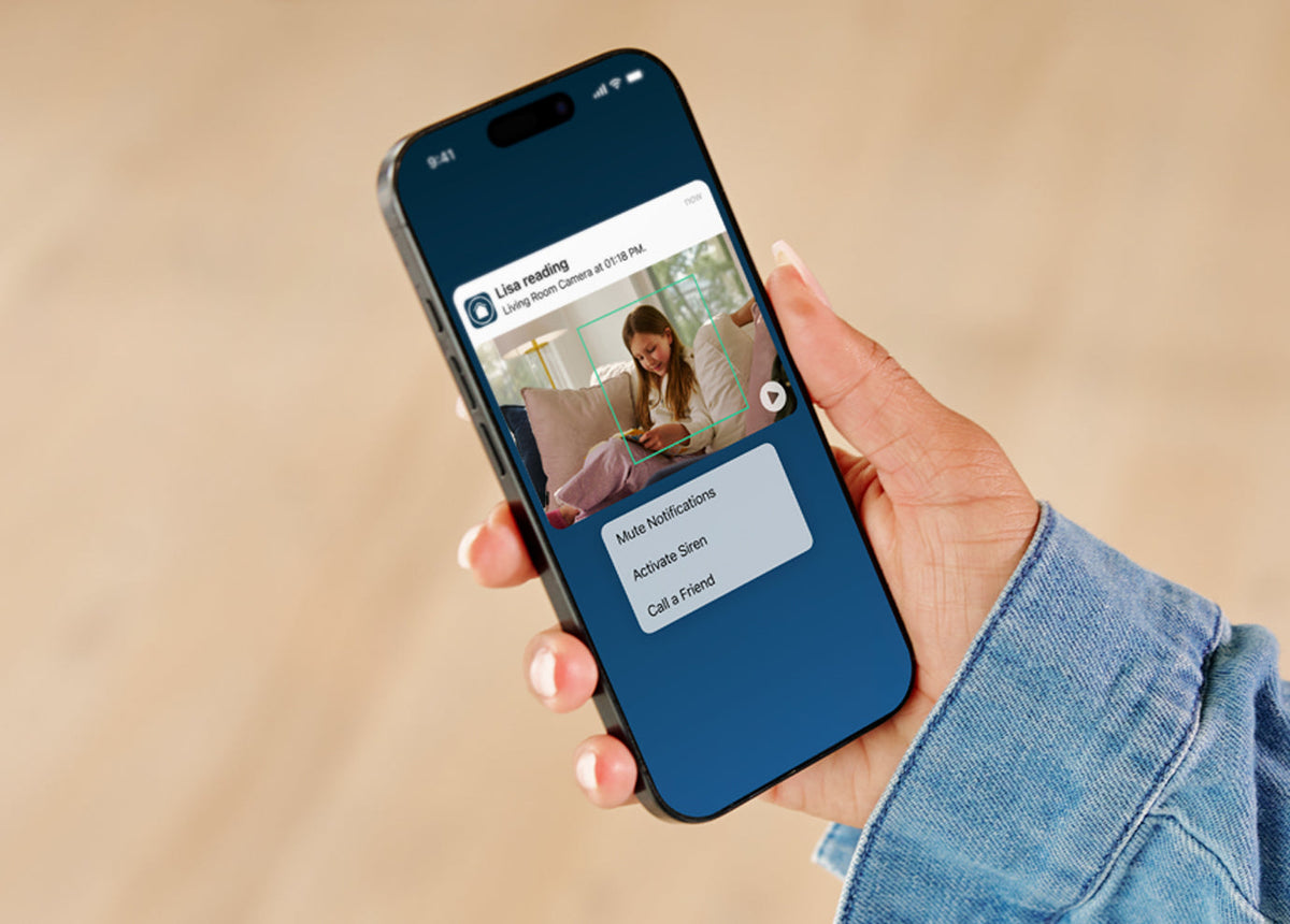 Hand holding a smartphone with a Arlo Secure app open on a beige background